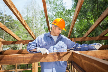 Naklejka na ściany i meble Construction Worker Measuring Timber Frame
