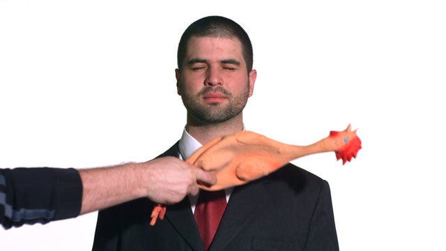 Businessman gets hit with rubber chicken. Slow motion. 