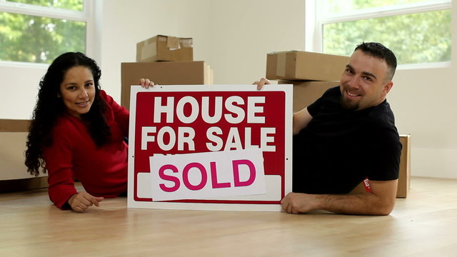 Couple in new home with sign