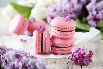 French pink macarons with lilac flowers on white wooden backgrou