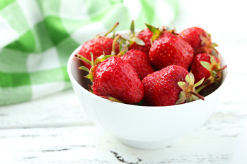 Strawberries berry in bowl on white wooden background