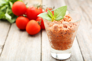 Glass with granita from fresh tomatoes on grey wooden background