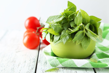 Tomatoes and basil leaves on white wooden background