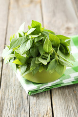 Basil leaves in bowl grey wooden background