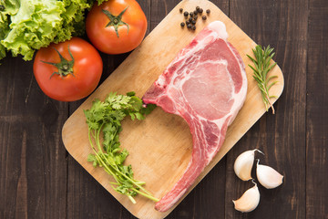 Fresh Raw Pork Chops and vegetable on wooden background.
