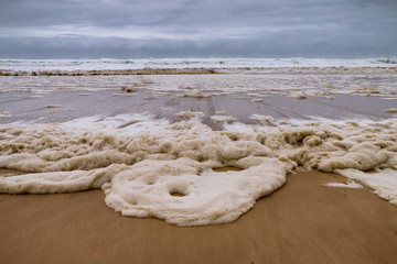 Stormy Seas and Skies and Beach covered in Sea Foam