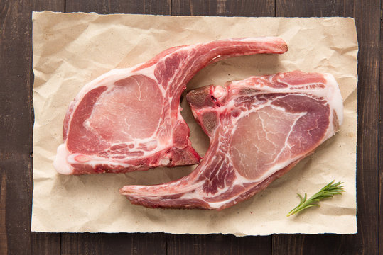 Top view raw pork chop steak on paper on wooden background