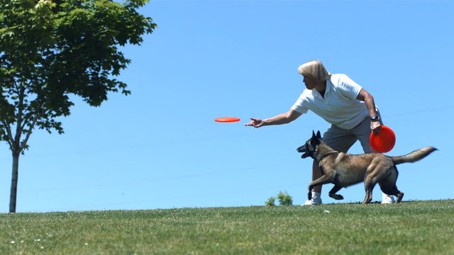 Woman throws plastic disc to dog, slow motion