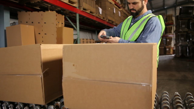 Man in shipping warehouse scans labels on boxes