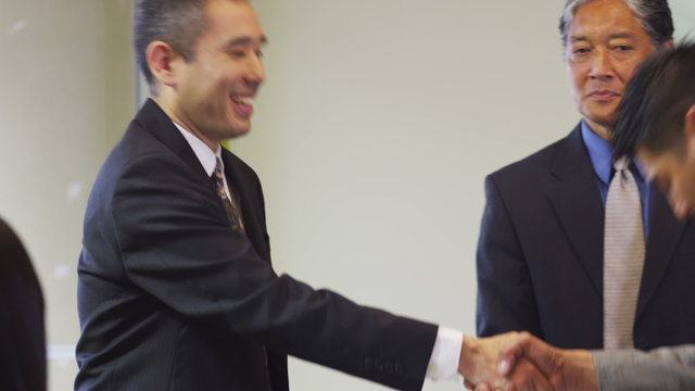 Group of Asian businesspeople shake hands and bow