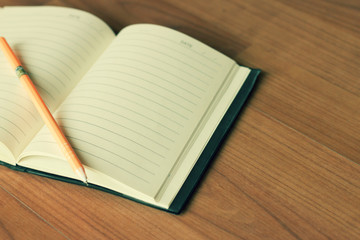 Vintage style of open notebook and pen on the old wooden floor.