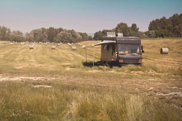 Fototapeta premium Summer Caravan Parked on Meadow with Hay Bales