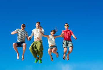 Happy young group of people jumping in the blue sky