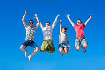 Happy young group of people jumping in the blue sky