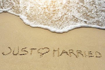 just married written on sand beach near sea