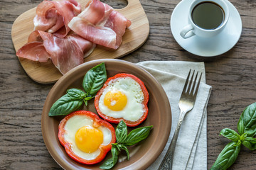 Fried eggs with prosciutto on the wooden table