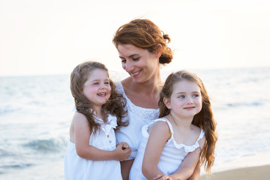 Close-up portrait of mother with daughters smiling on the beach