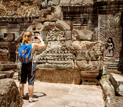 Tourist photographing bas-reliefs in temple. Angkor, Cambodia