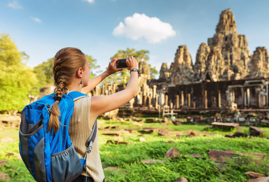 Young female tourist taking picture of Bayon temple, Angkor