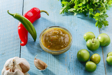 tkemali green sauce into a bowl on a wooden surface