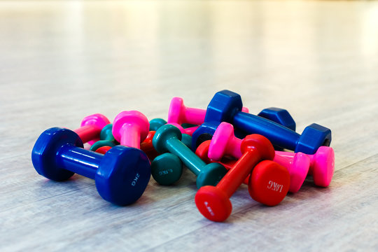 Group of colored dumbbells on the floor in the gym