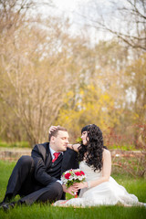 bride and groom sitting on the green grass