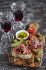 bruschetta with  ham, olives, cherry tomatoes in olive Board and red wine 