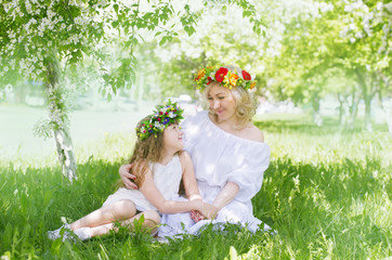 Mom and daughter in floral garlands look at each other