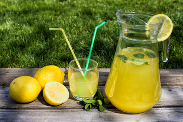 Lemonade in the jug and lemons on the table outdoor