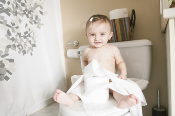 Toddler ripping up toilet paper in bathroom