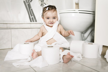 Toddler ripping up toilet paper in bathroom