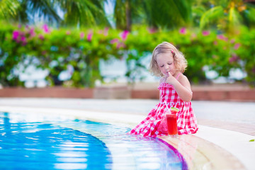 Naklejka premium Little girl drinking juice at a swimming pool