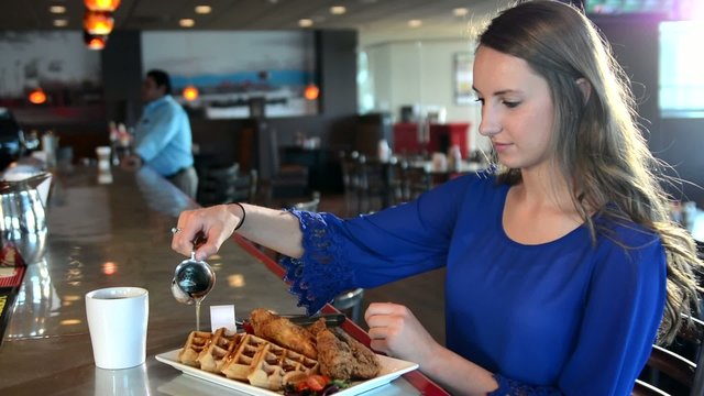 Woman pouring syrup on her waffles in a cafe
