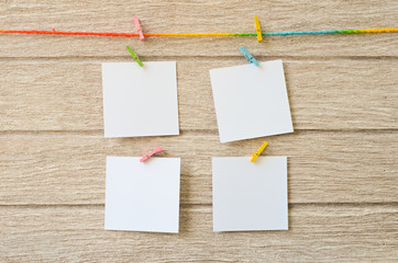 empty white photo frames hanging with clothespins on wooden background 