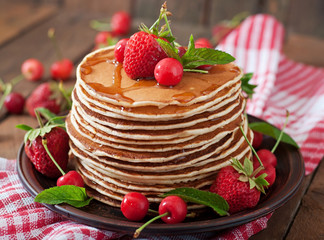 Pancakes with berries and syrup in a rustic style