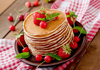 Pancakes with berries and syrup in a rustic style