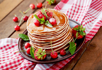 Pancakes with berries and syrup in a rustic style