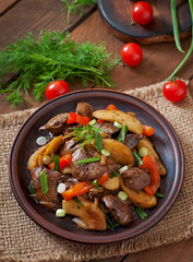Roast chicken liver with vegetables on wooden background
