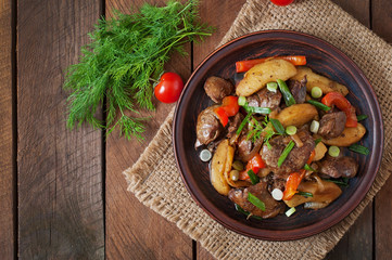 Roast chicken liver with vegetables on wooden background