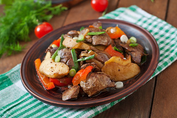 Roast chicken liver with vegetables on wooden background