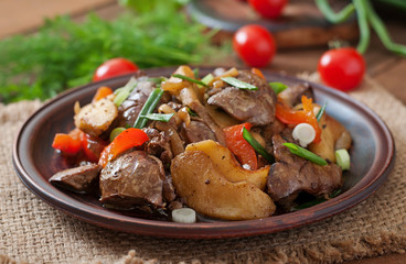 Roast chicken liver with vegetables on wooden background