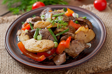 Roast chicken liver with vegetables on wooden background