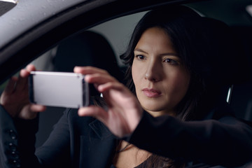 Woman taking a selfie as she waits in her car