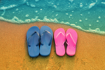 Fototapeta na wymiar Romantic beach scene. Female and male flip flpp sandals on the beach