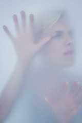 Blonde woman touching frosted glass