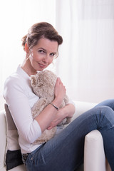 Frau sitzt mit Teddy im Sessel