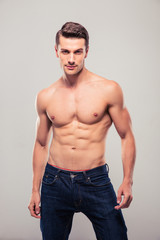 Sexy confident man posing over gray background