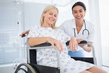 Doctor and patient in wheelchair smiling at camera 