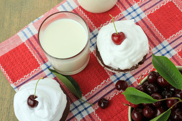 Chocolate cupcakes with cherries on wooden background. top view