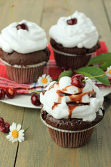 Chocolate cupcakes with cherries on wooden background. top view